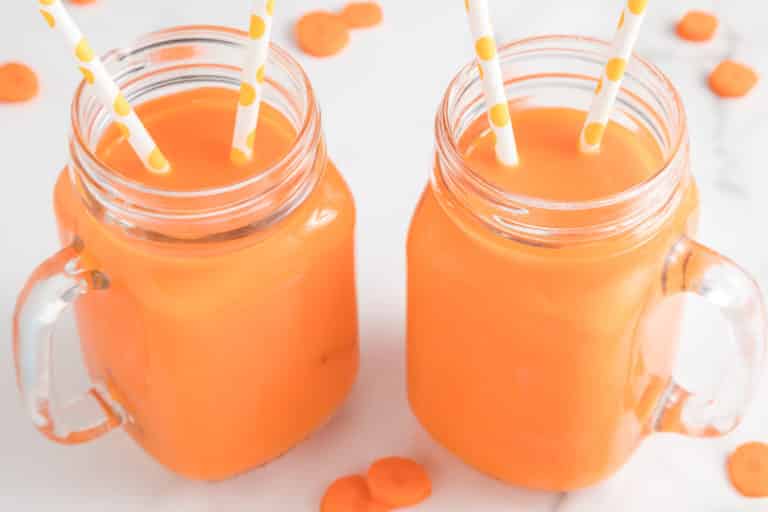 Two mason jar mugs with carrot juice, each has two straws.