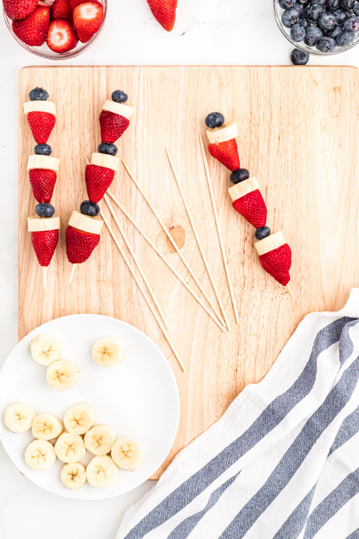 Assembled patriotic fruit kabobs on a wooden cutting board.