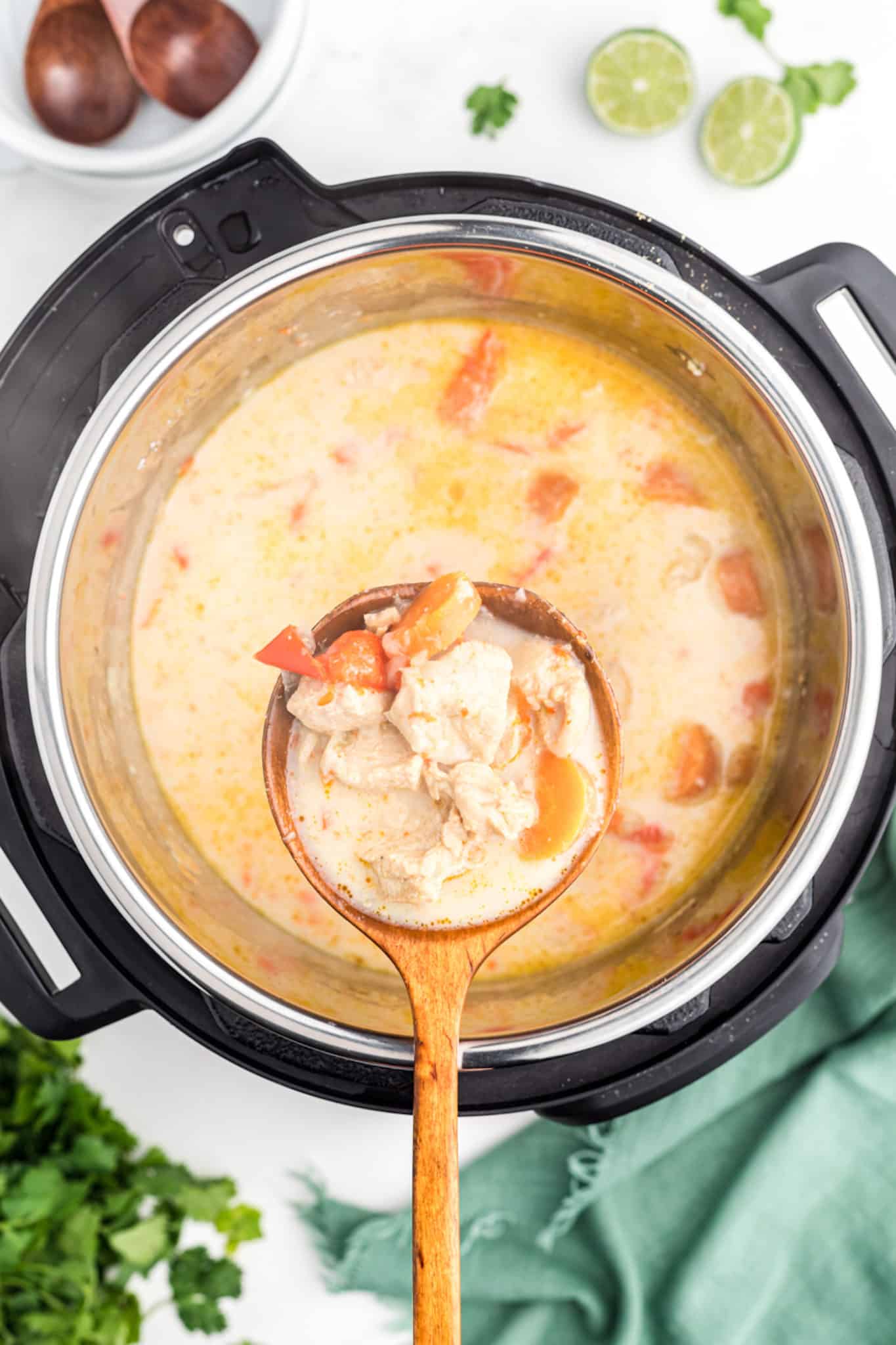 A ladle full of Thai Chicken Curry Soup over a full Instant Pot.