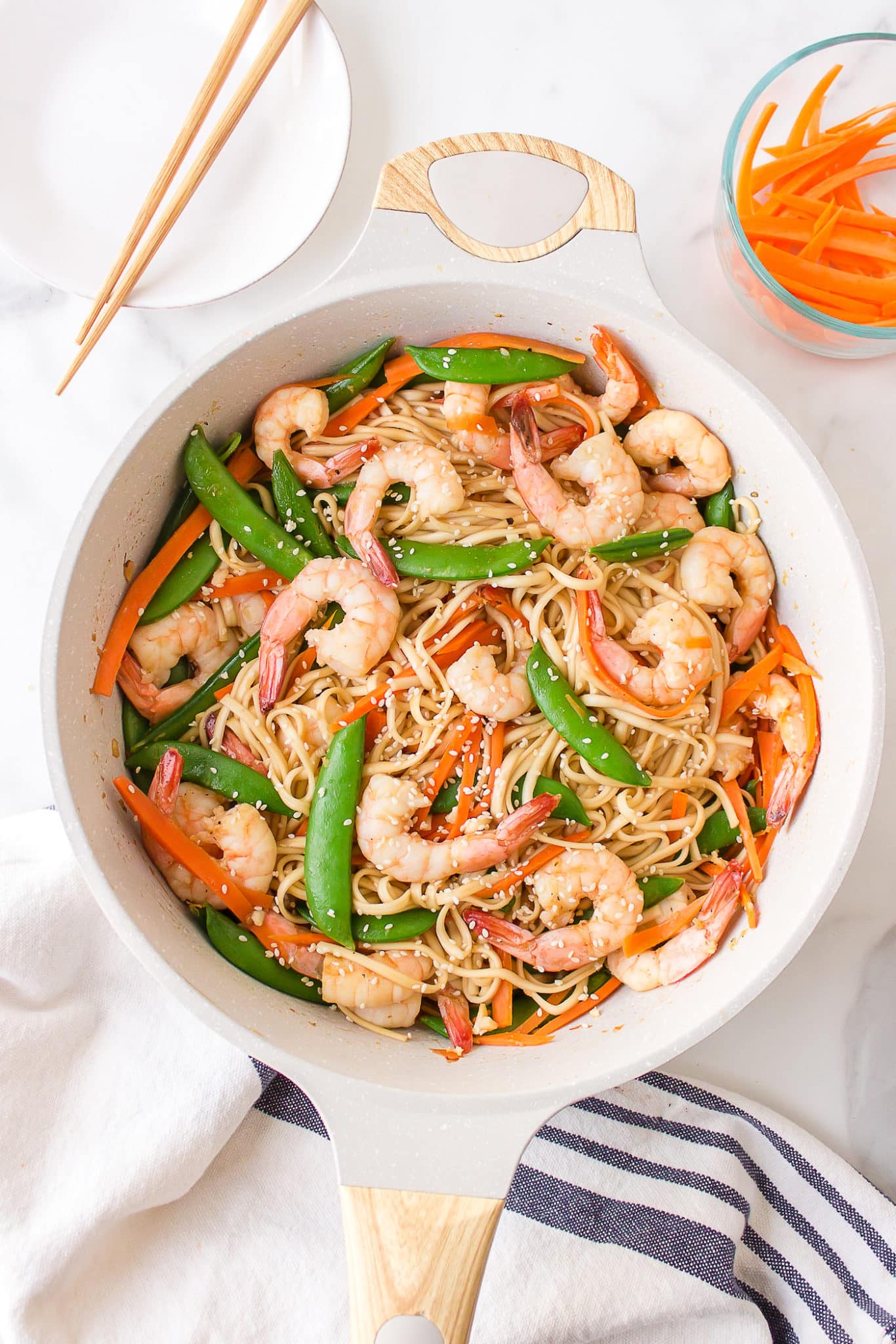 shrimp udon with veggies served in a white dish with chopsticks.