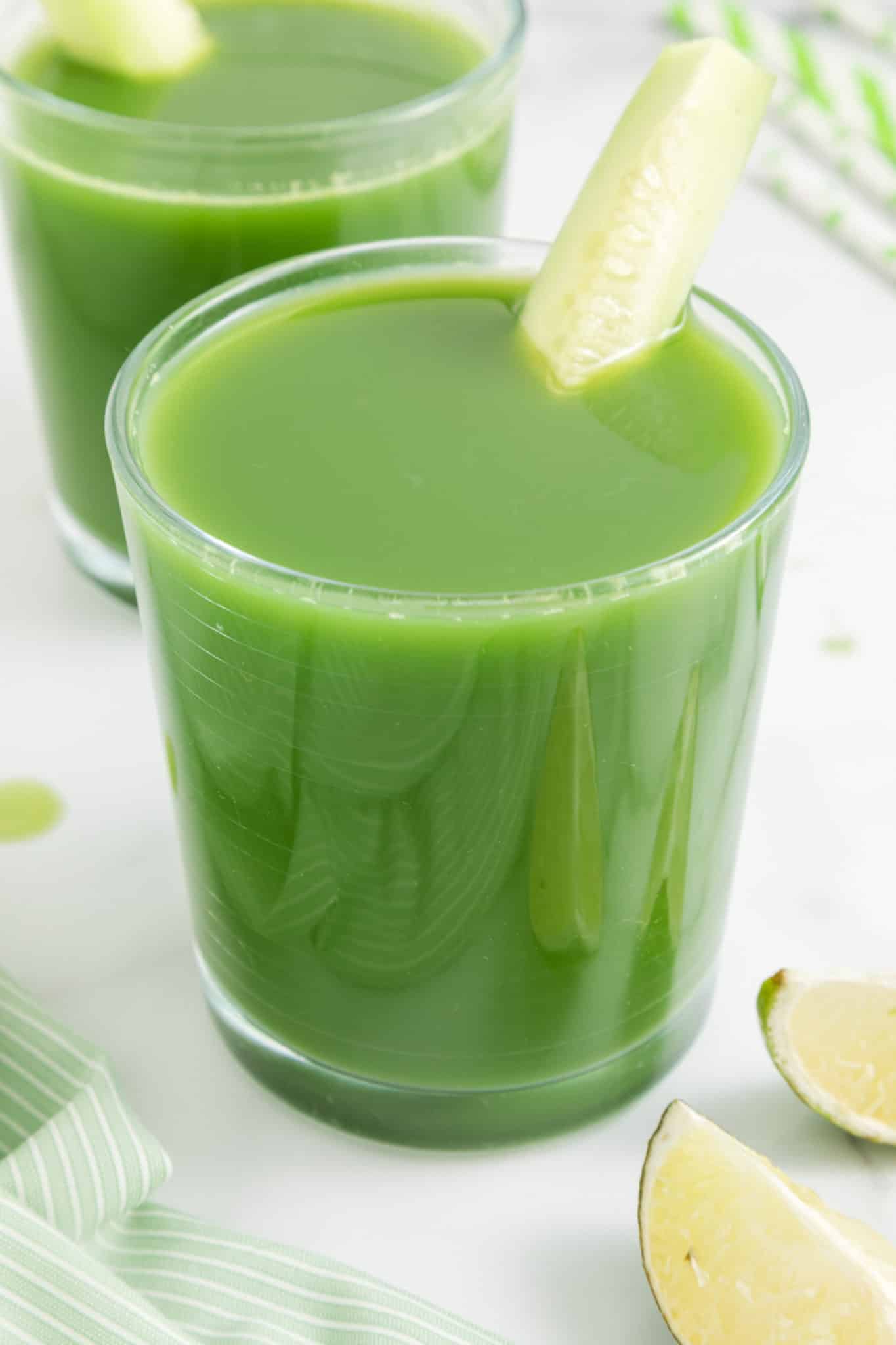 Top view of a glass of cucumber juice with a lime wedge on the rim.