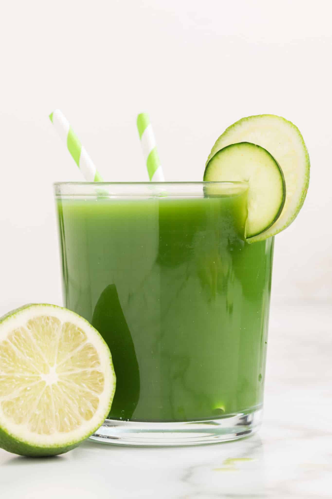 A glass of cucumber juice with lime wheels on the rim.