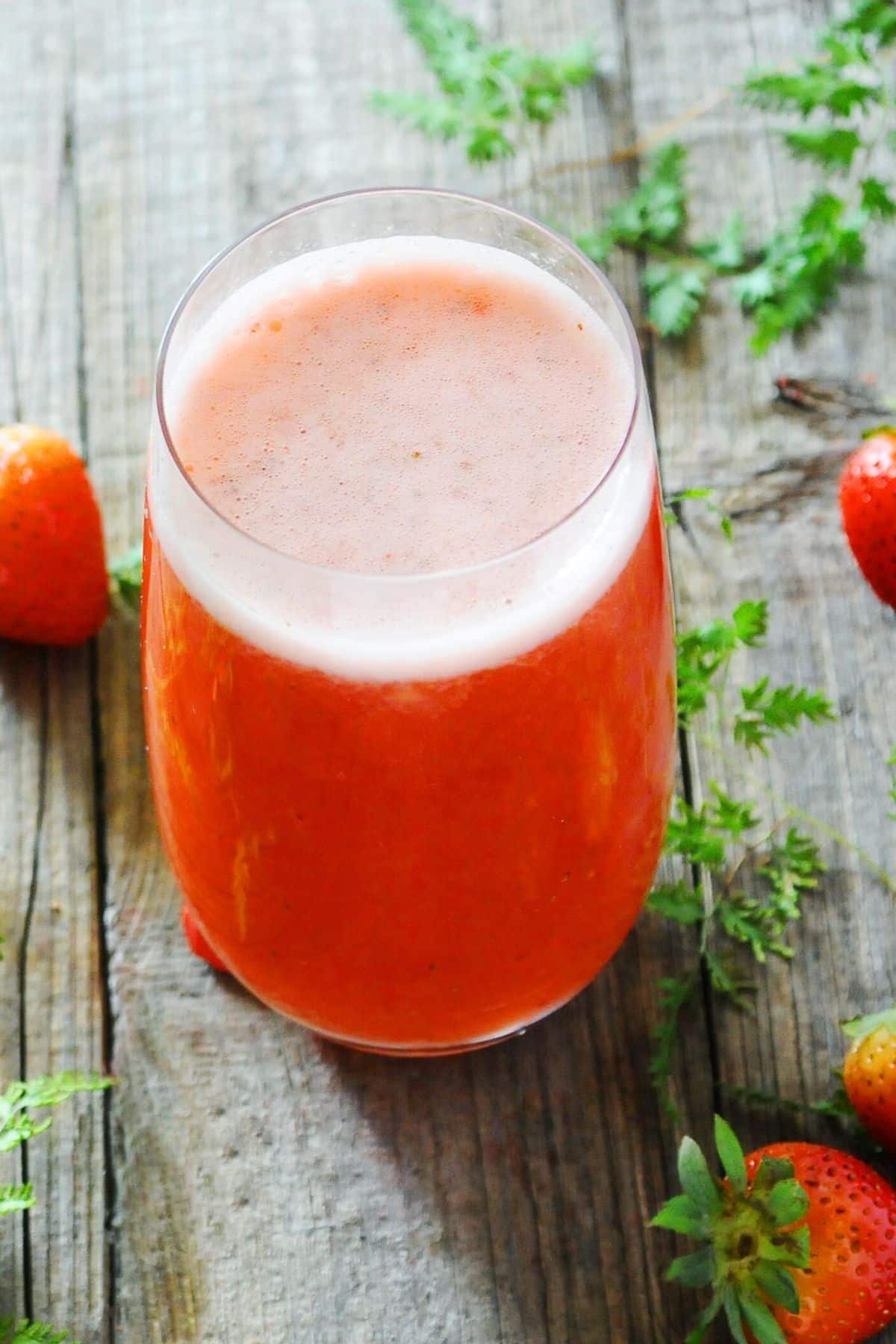 glass of strawberry juice with foam on top.