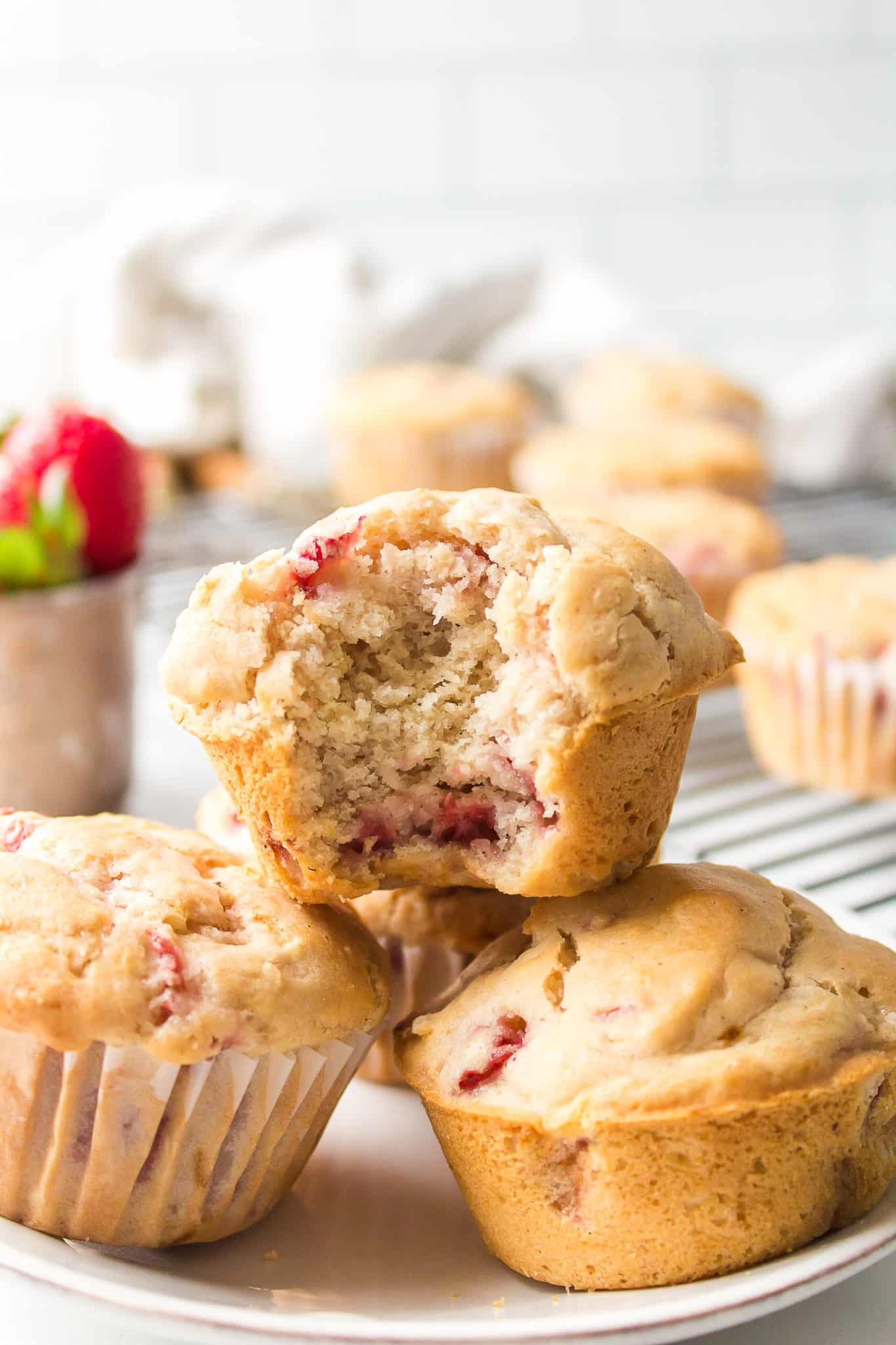 strawberry muffins stacked on each other with a bite taken out of one.
