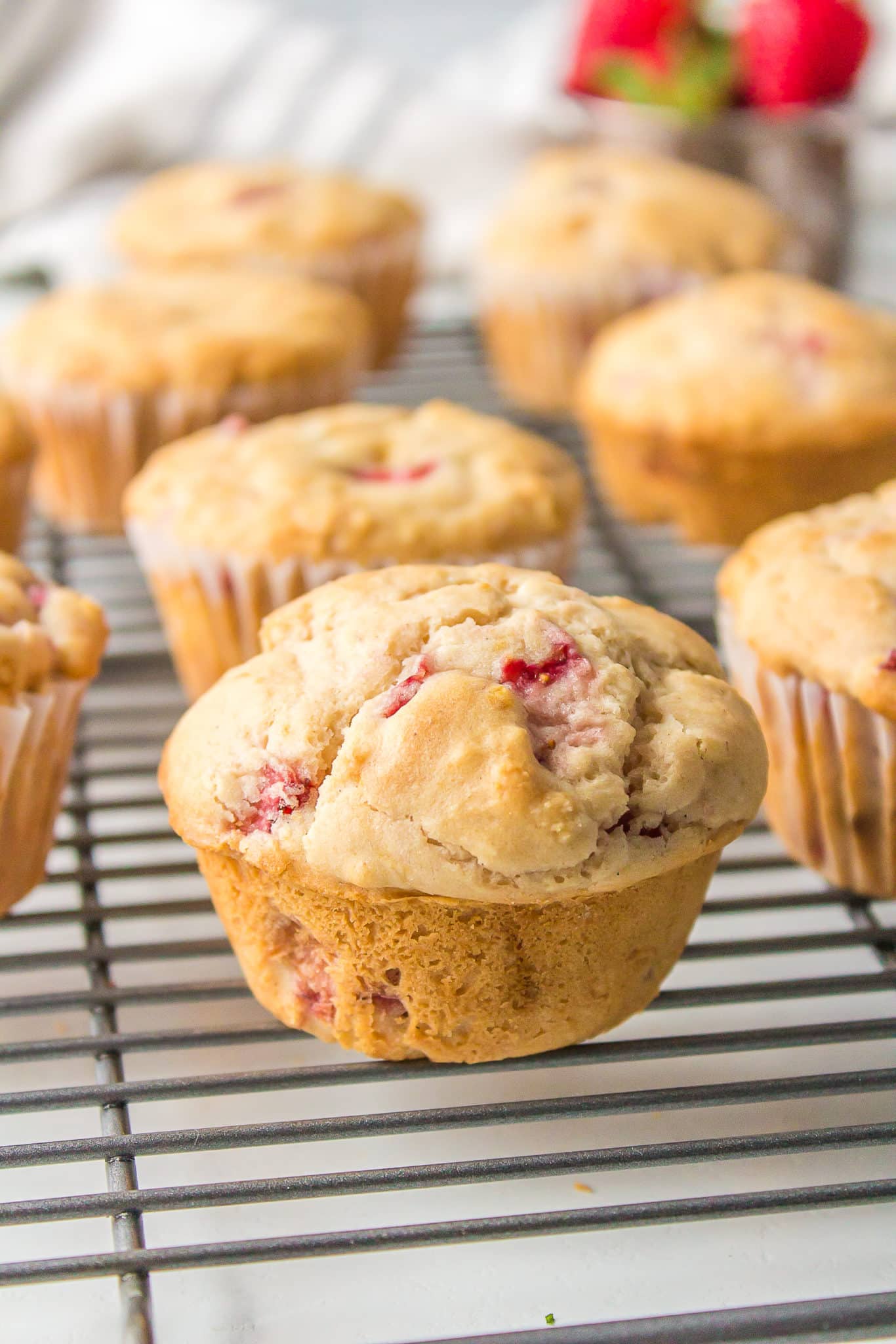 Gluten-free strawberry muffins lined up on a cooling rack.