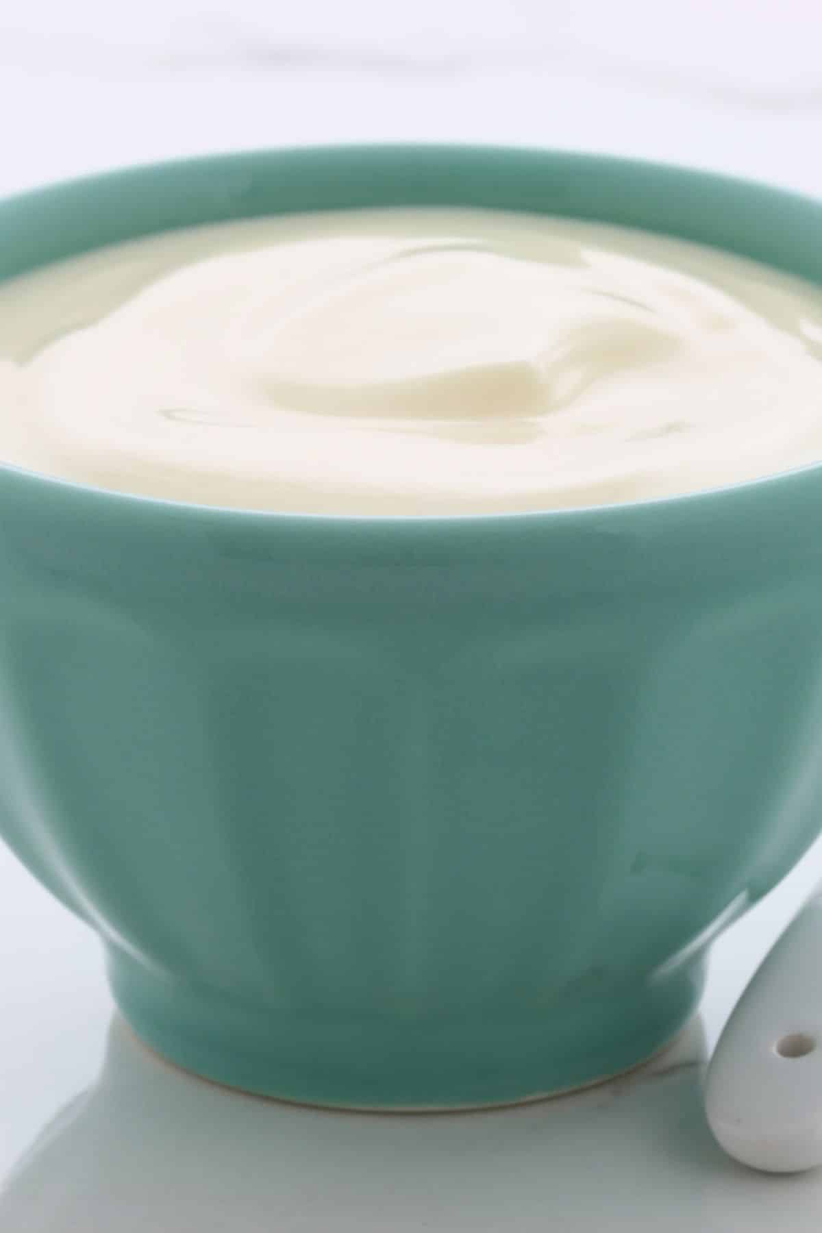 Small green bowl filled with plain yogurt.