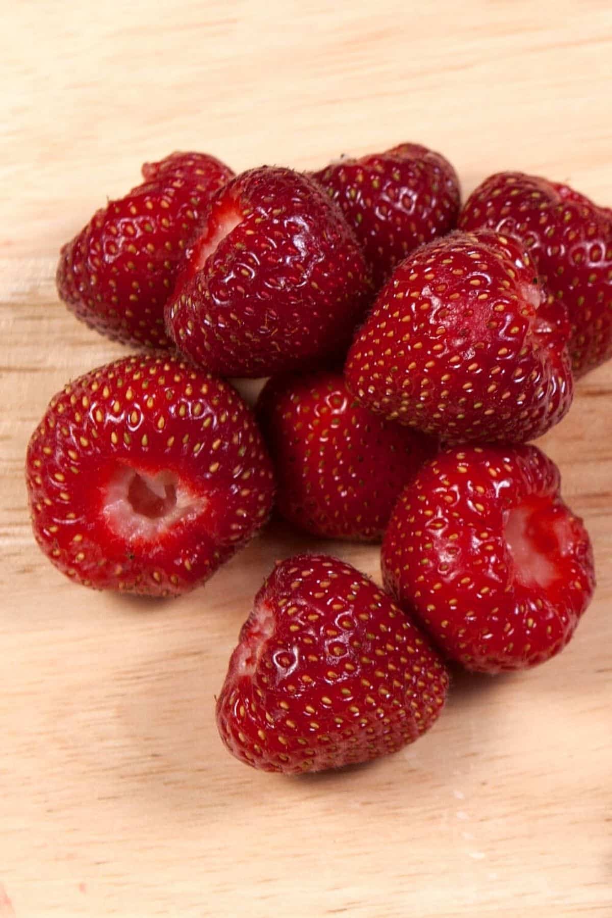 hulled strawberries on a cutting board.