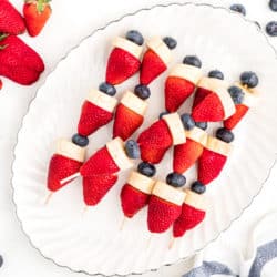 Red white and blue fruit kabobs on a white platter.