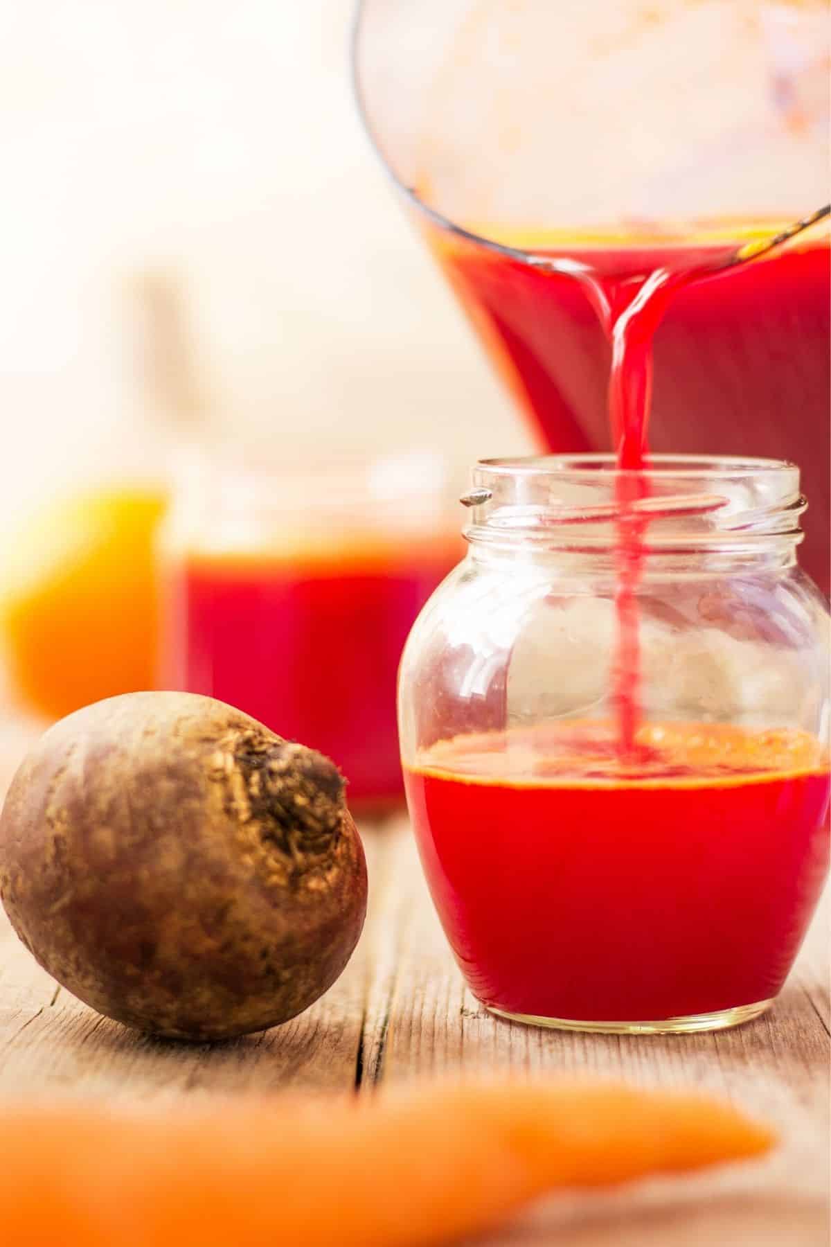 pouring carrot beet juice into glass.