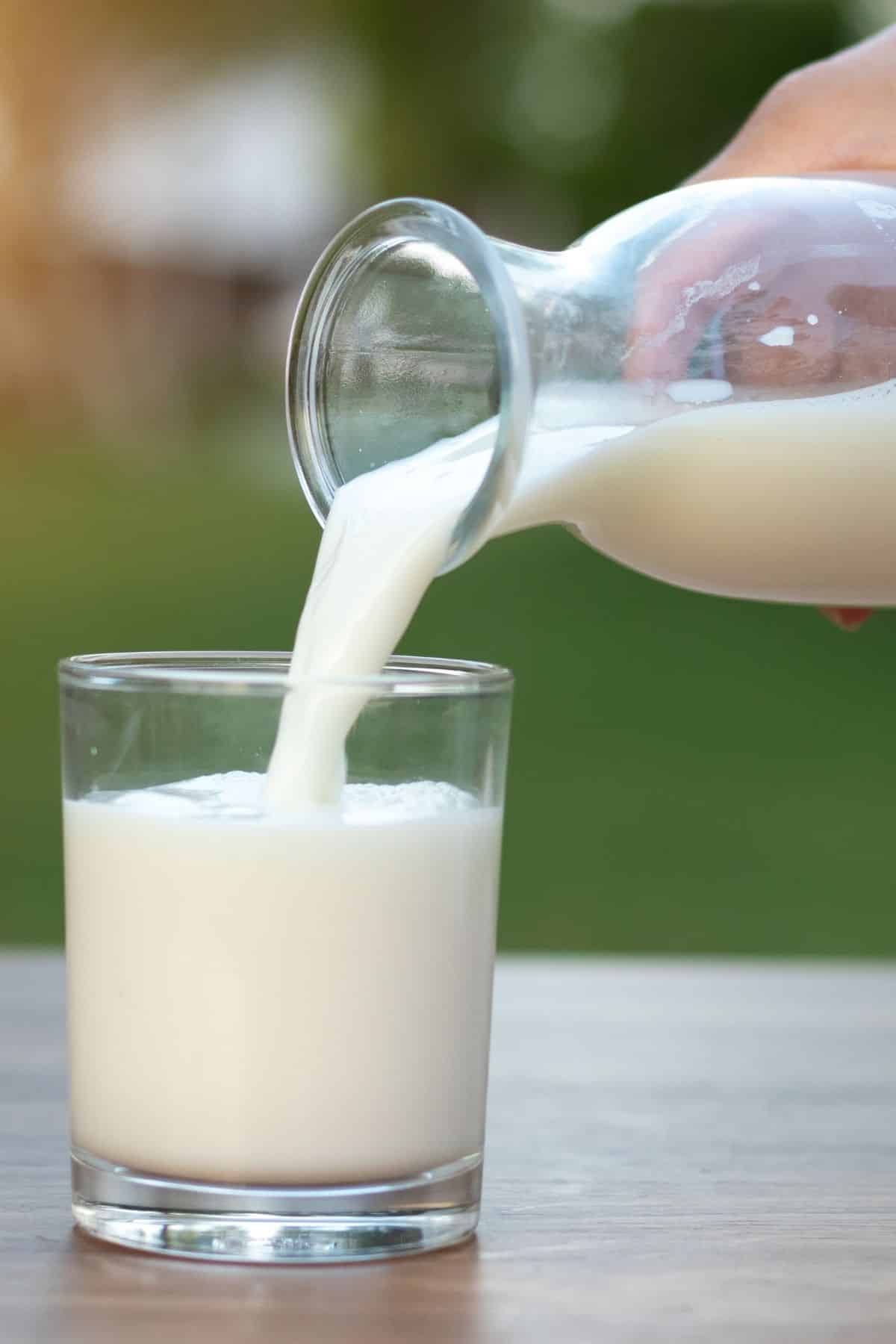 Raw milk being poured from a jar into a glass.