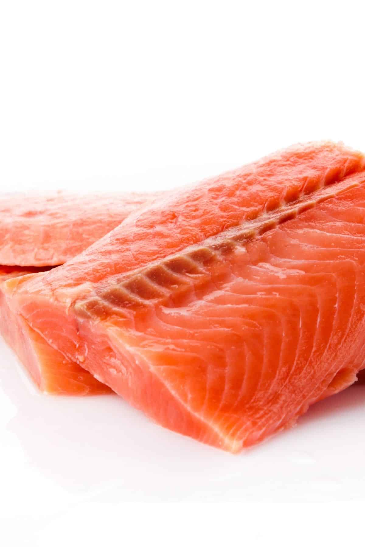 Raw salmon fillets on a white surface.