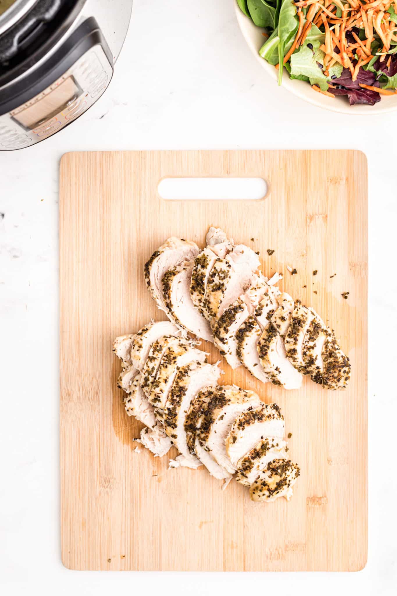 Sliced turkey tenderloin on a wooden cutting board.