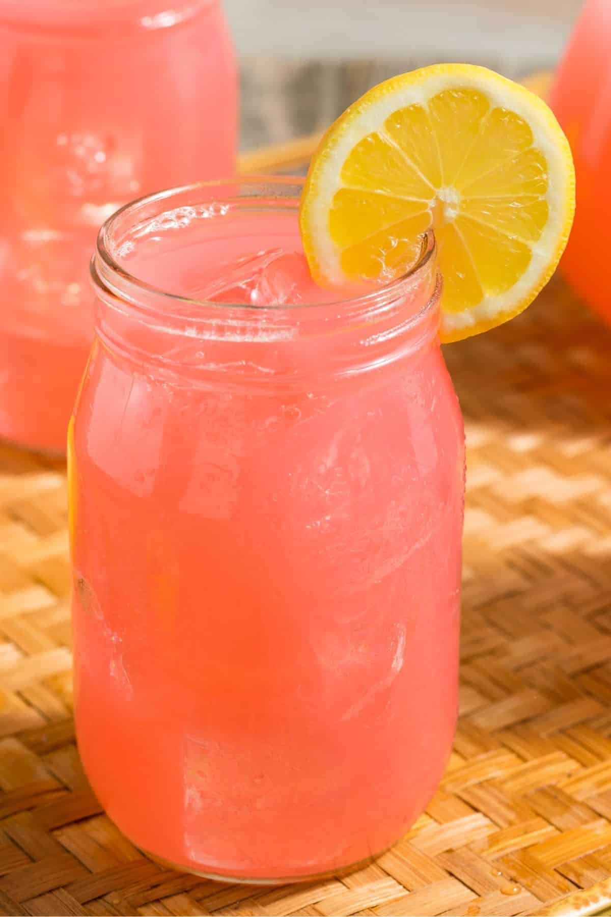 pink lemonade in a jar with a slice of lemon.