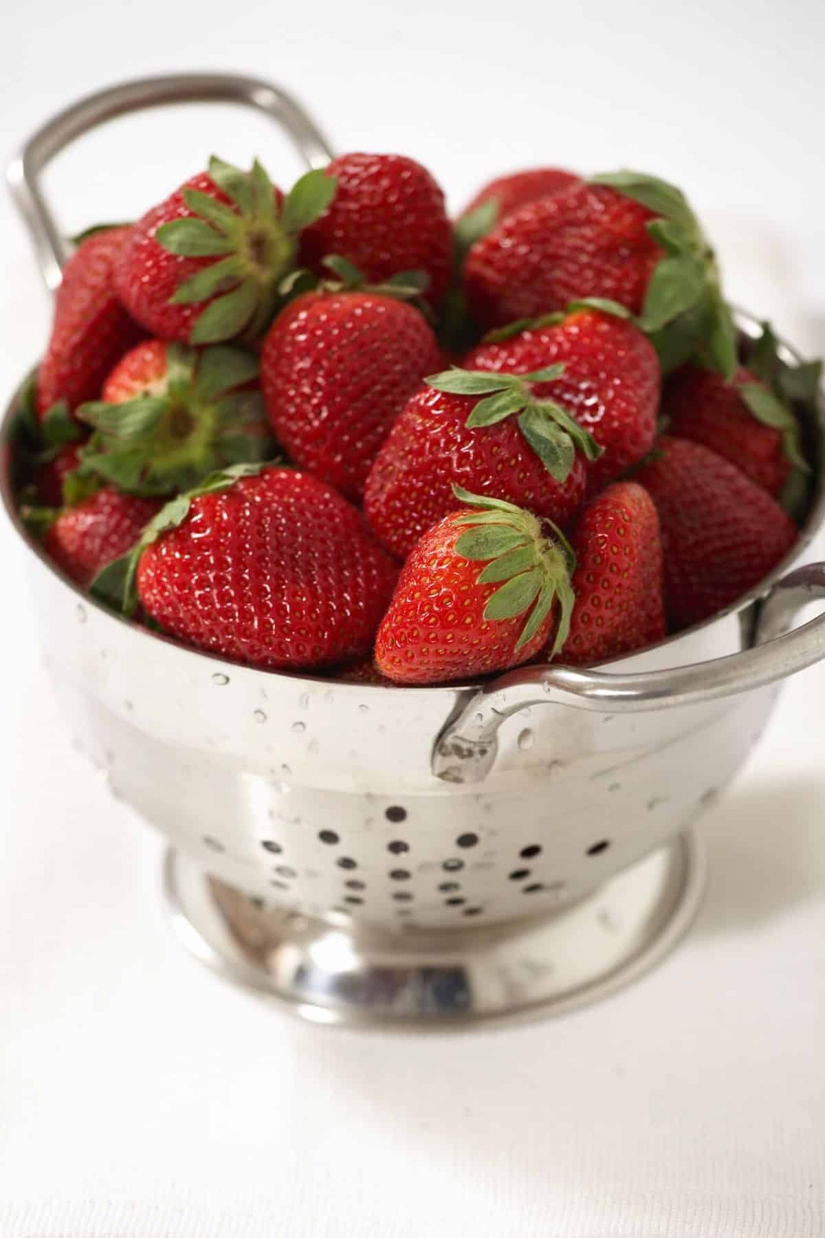 strawberries in a colander ready to be juiced.