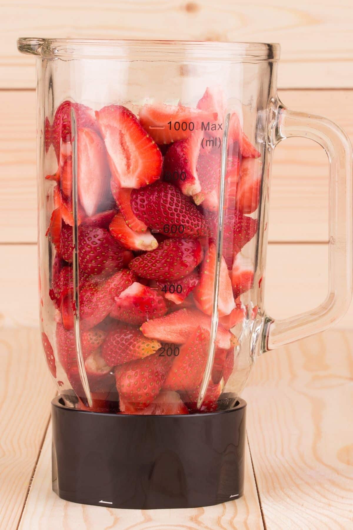 quartered strawberries in a blender jar ready to be blended.