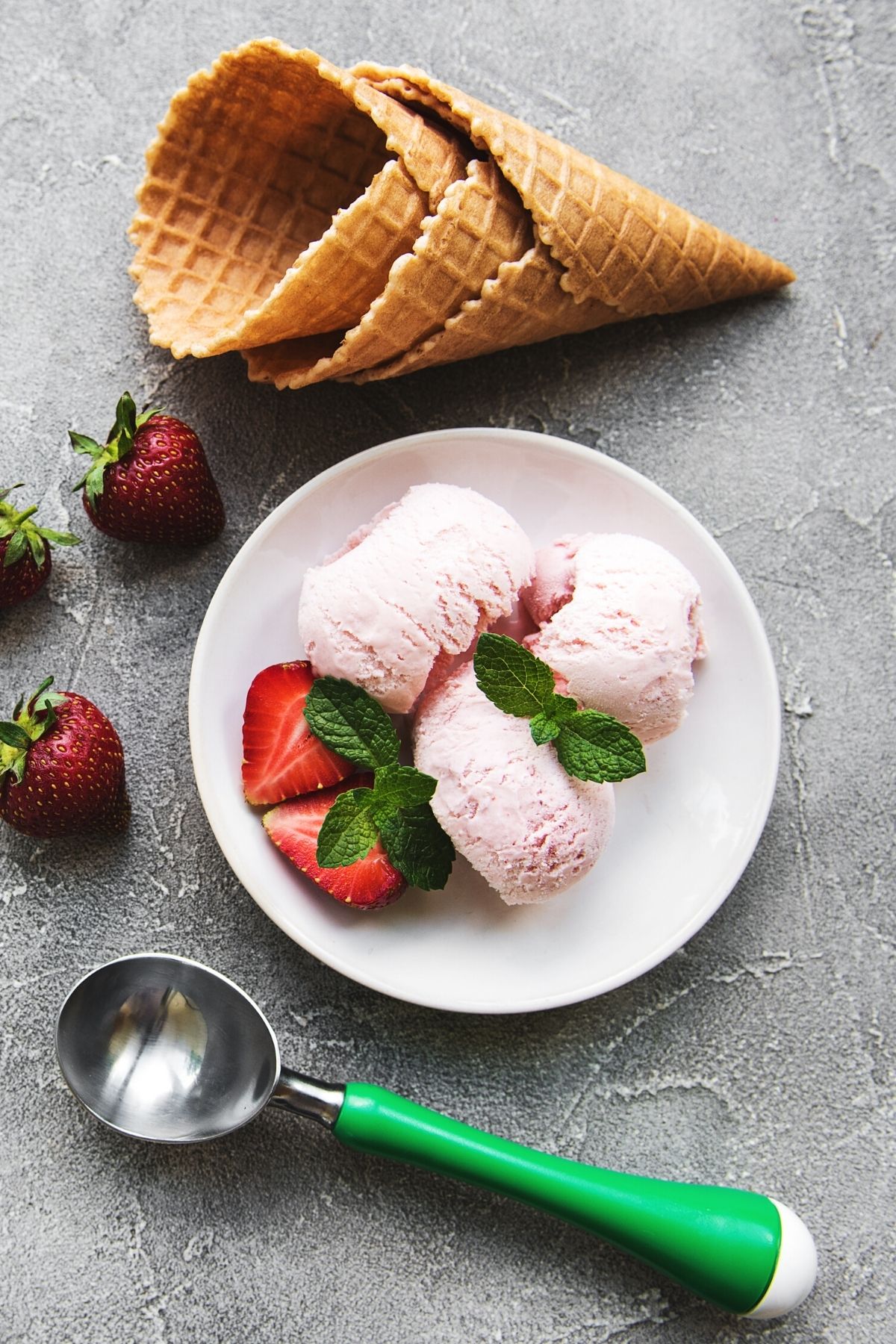 vegan strawberry ice cream served with fresh strawberries and waffle cones.