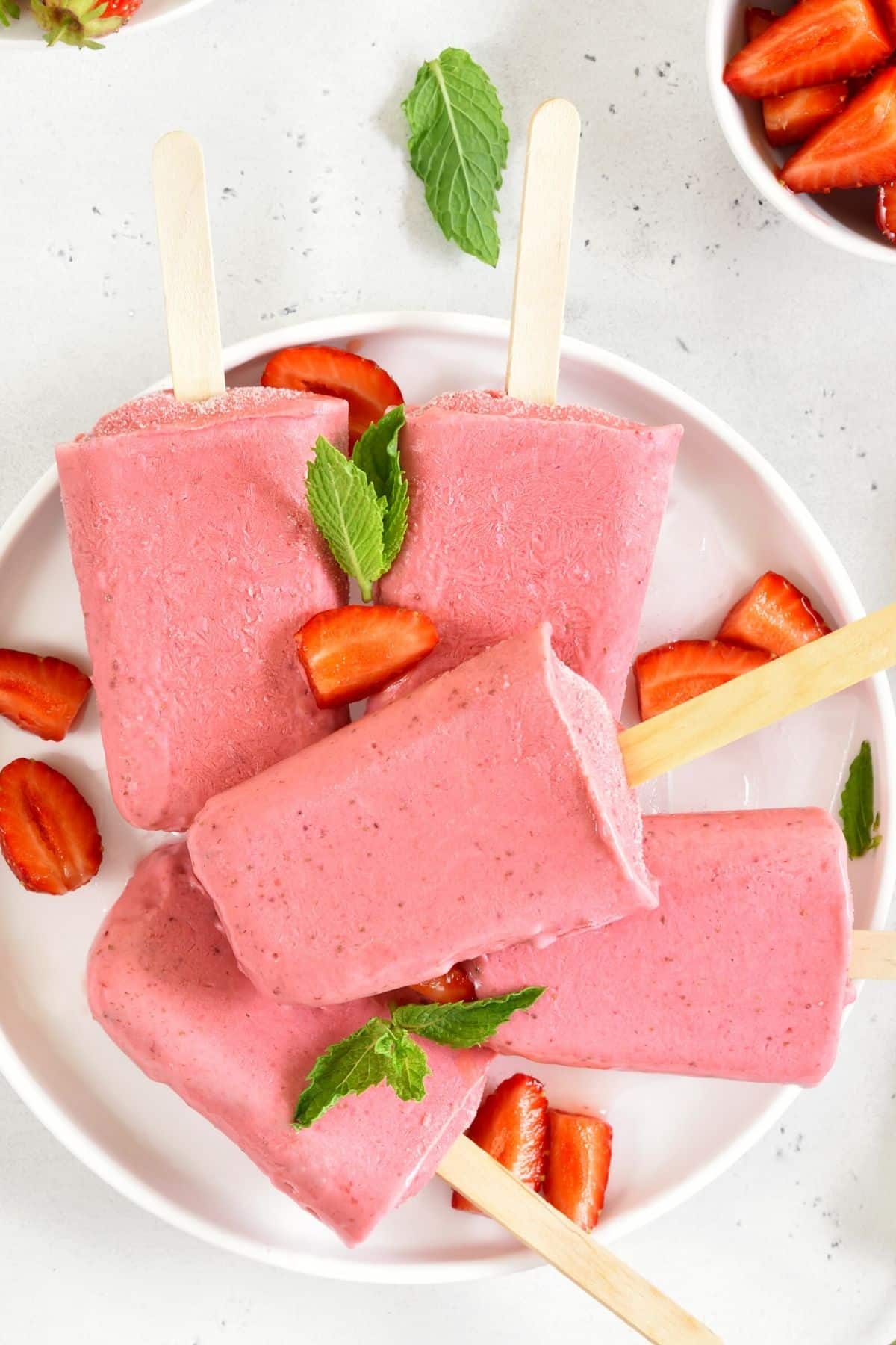 frozen strawberry popsicles on a plate.