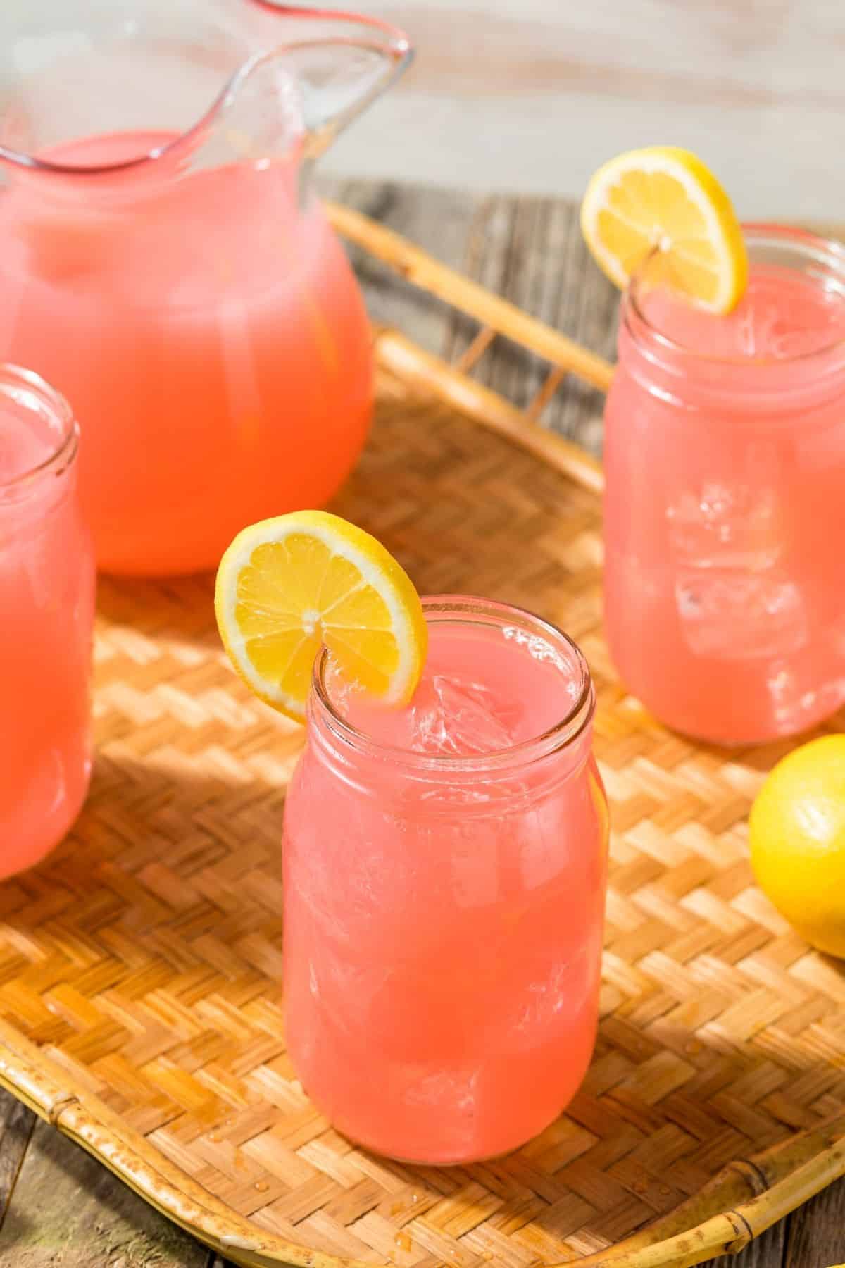 jars of kombucha lemonade with lemon slices on table with pitcher.