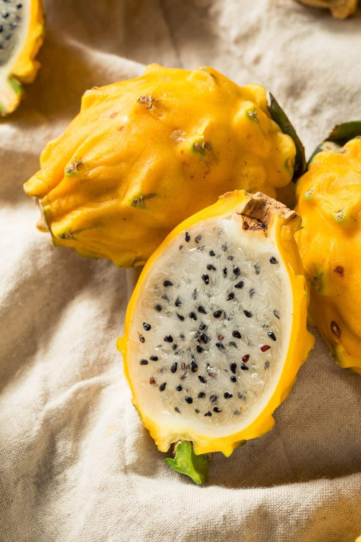 several yellow dragon fruit cut in half on a table.