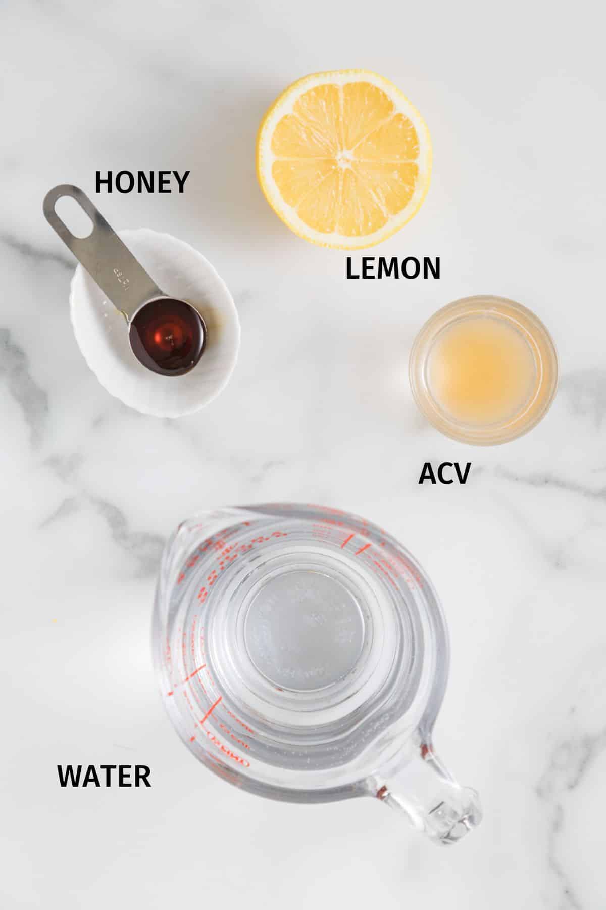 Ingredients to make a healthy ACV drink on a white surface.