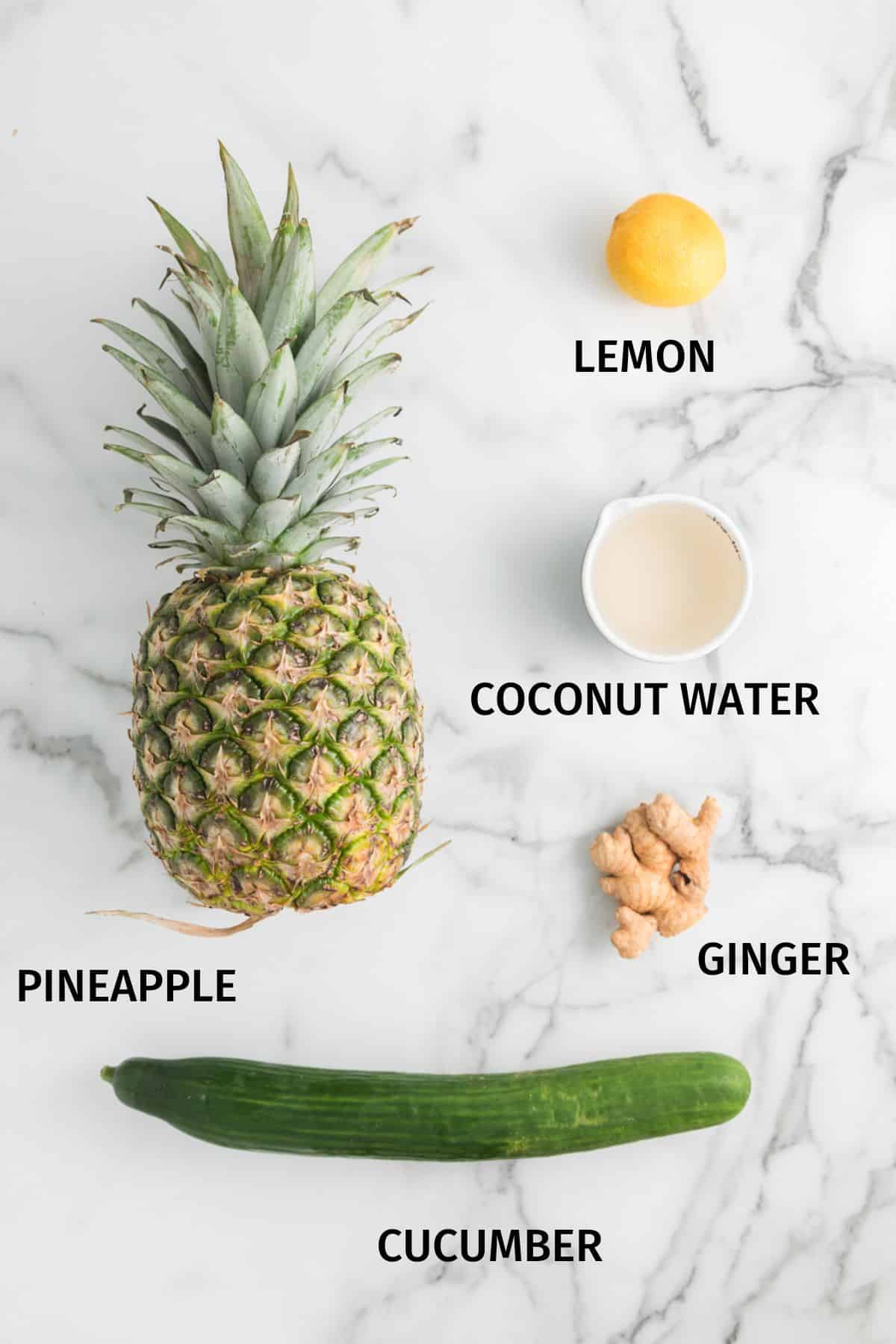 Ingredients for pineapple cucumber juice on a white marble surface.