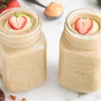 Two handled mason jars filled with strawberry zucchini smoothie.