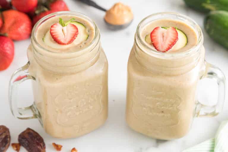 Two handled mason jars filled with strawberry zucchini smoothie.
