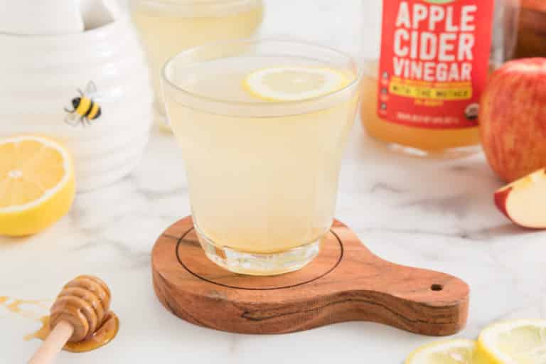 A glass of lemon apple cider vinegar water with a floating lemon wheel.