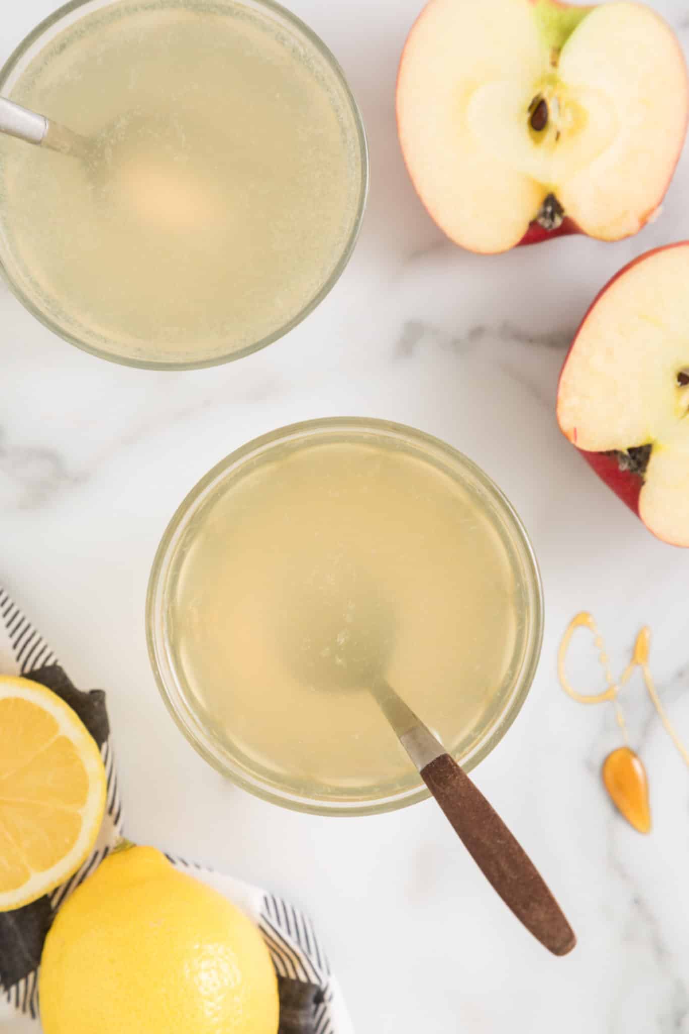 Spoons in glasses of apple cider vinegar drink.