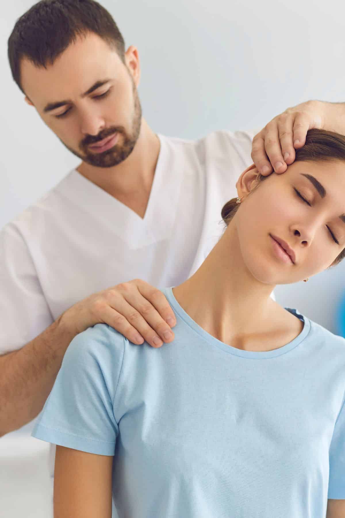 Male chiropractor working on the shoulder of a female patient.