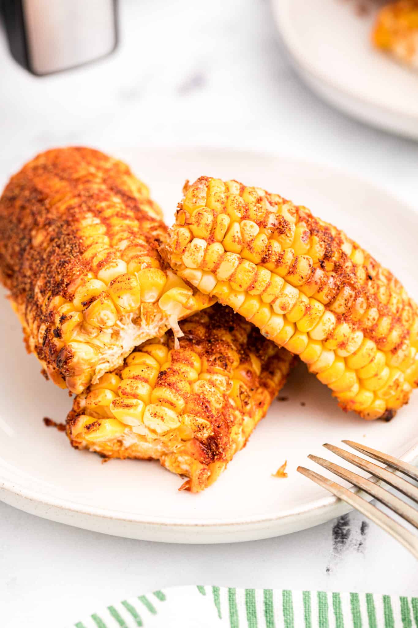 Seasoned air fryer corn ribs on a white plate.