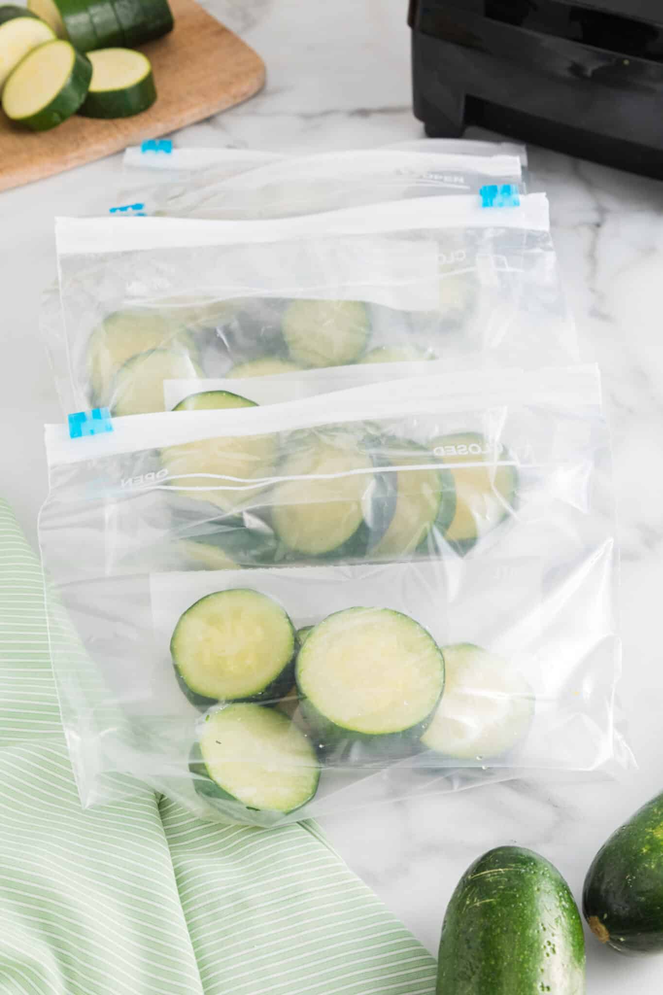 Frozen zucchini rounds in small ziploc baggies on a counter.