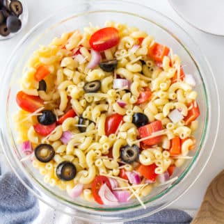 Gluten free pasta salad with tomatoes and peppers in a glass bowl.