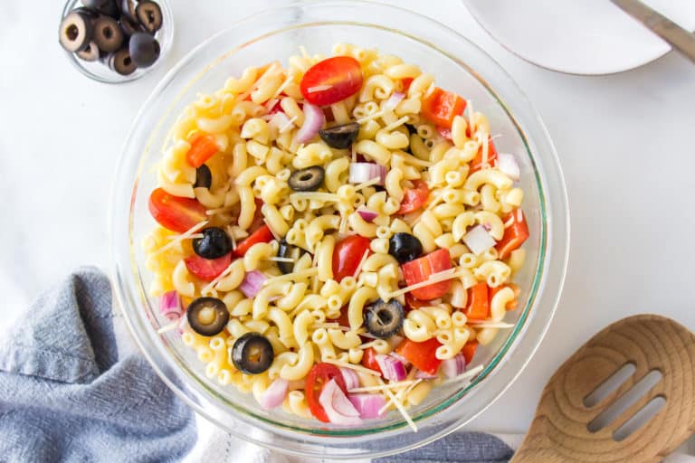 Gluten free pasta salad with tomatoes and peppers in a glass bowl.