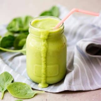 green smoothie in a glass with pink straw.