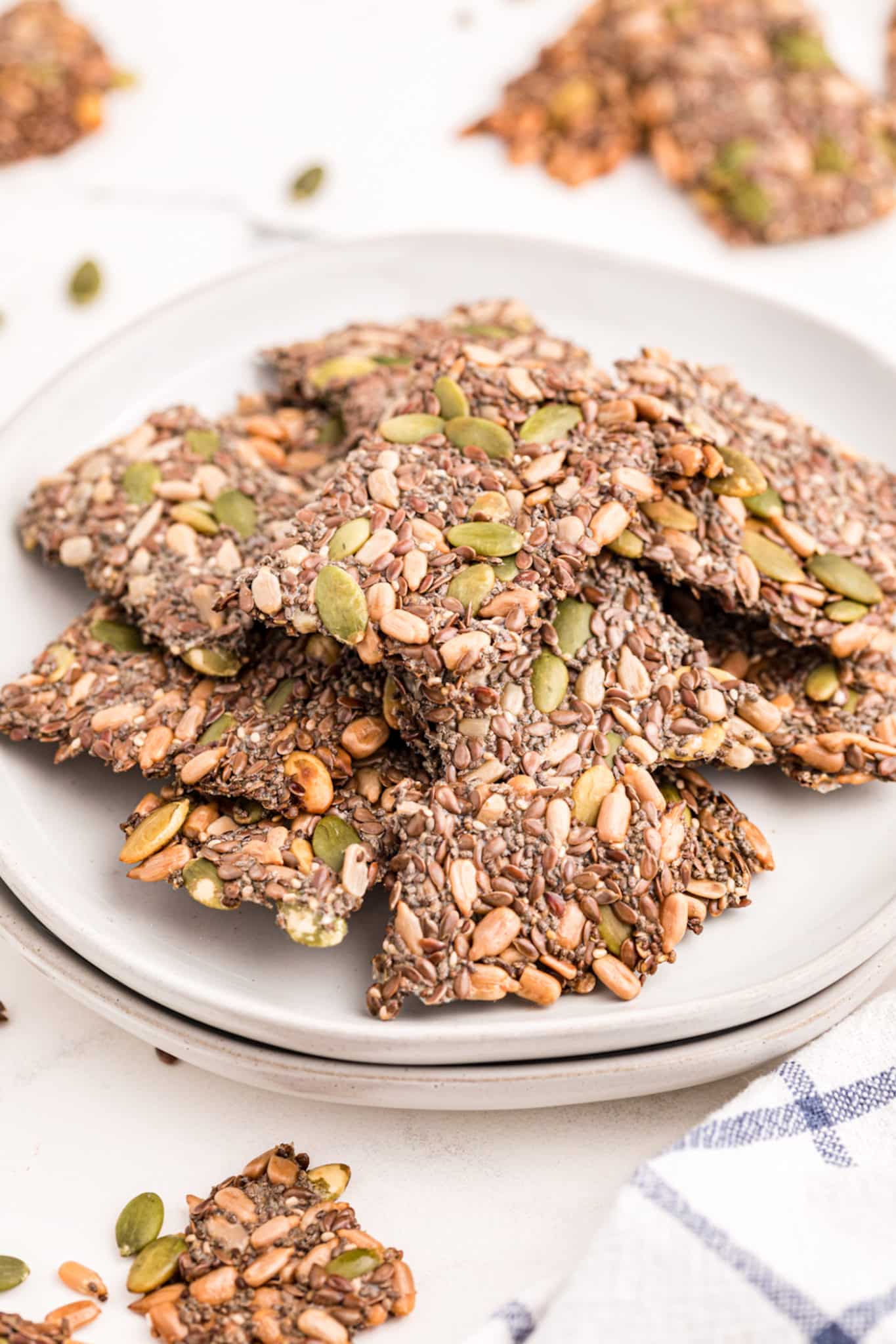 Homemade seed crackers piled up on a white plate.