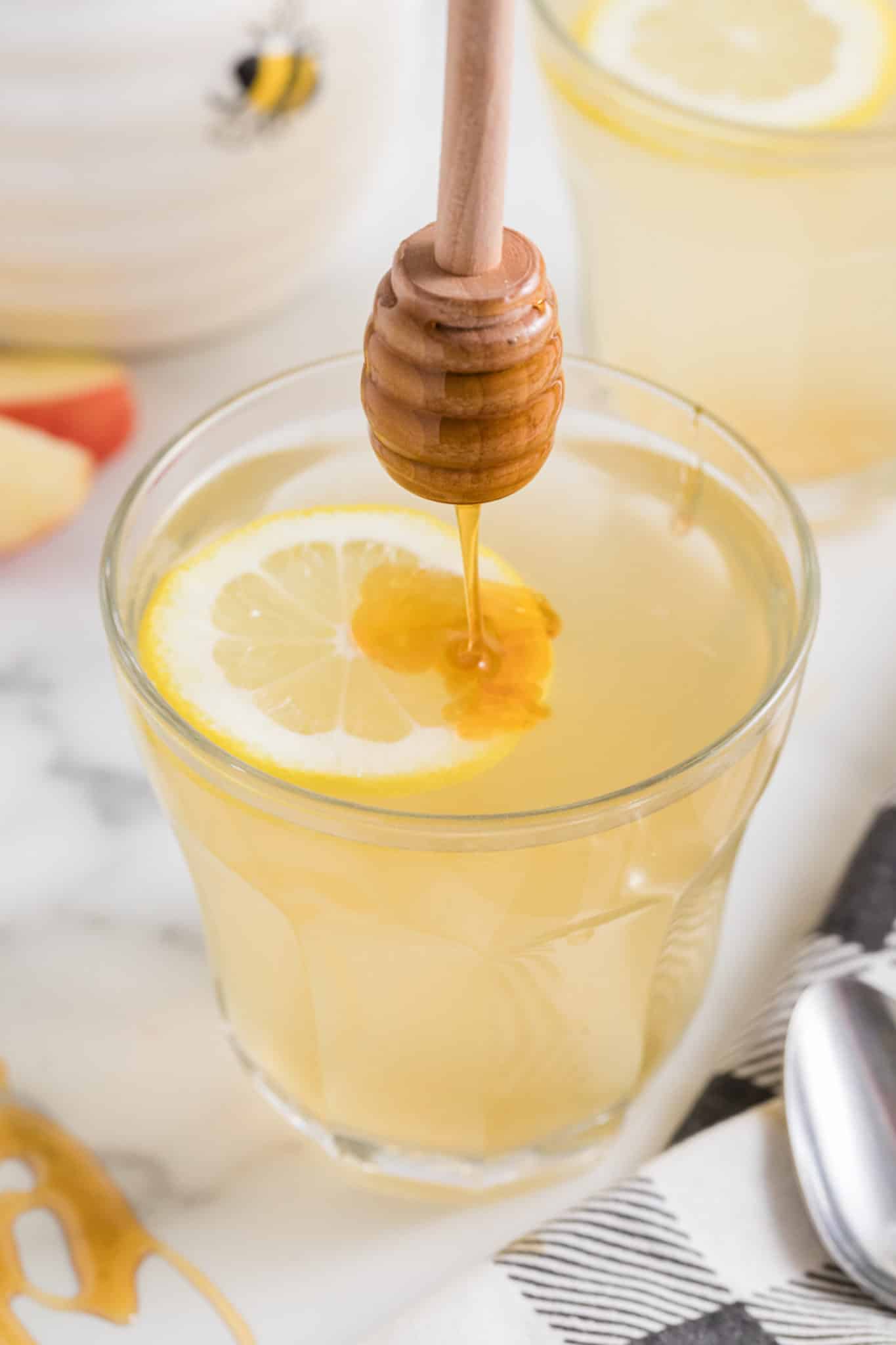 Drizzling honey into a glass of lemon ACV drink.