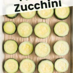 Frozen zucchini rounds on a parchment lined baking sheet.