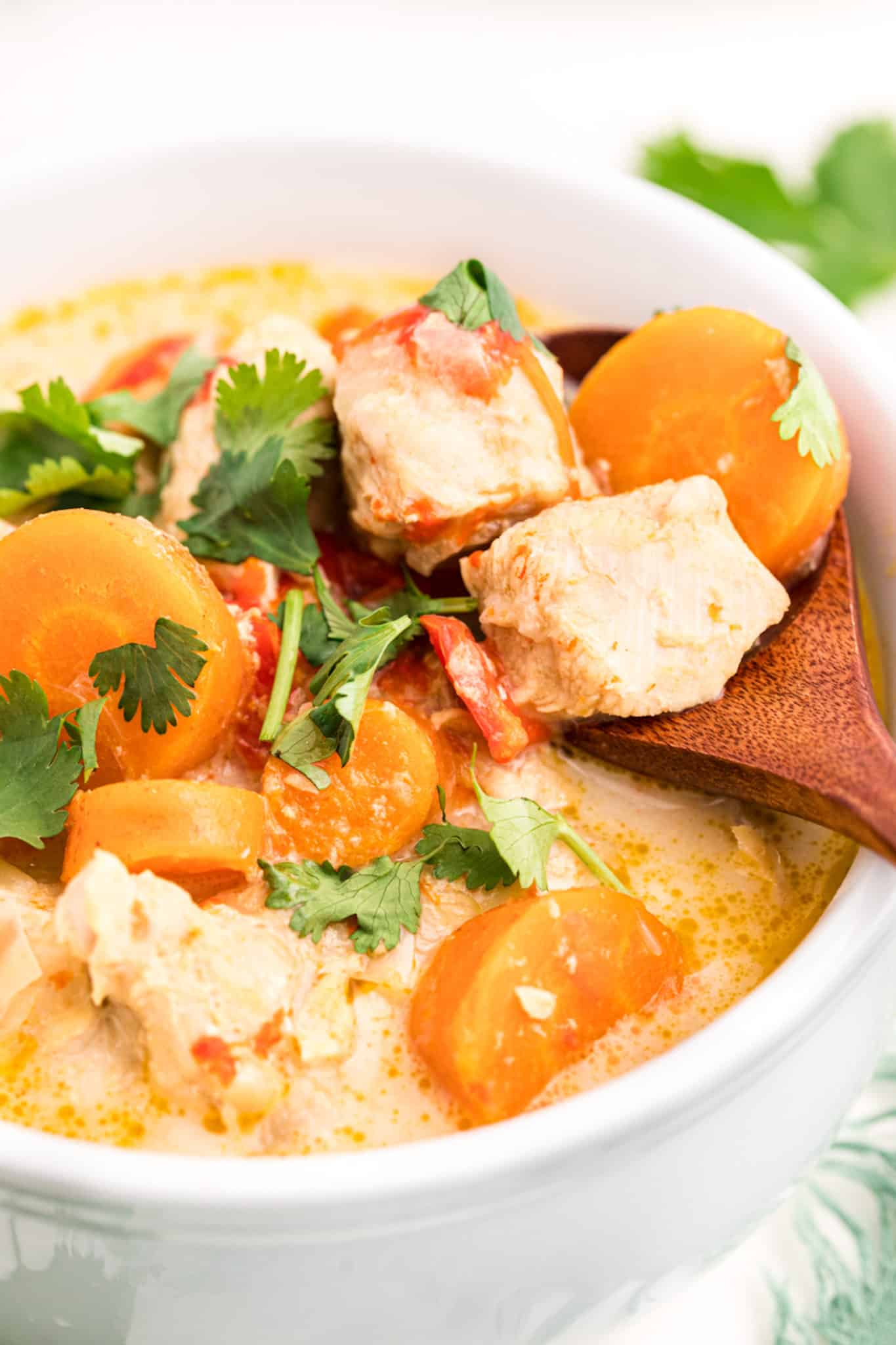 up close photo of thai green curry soup in a bowl with a vegetables and chicken chunks.