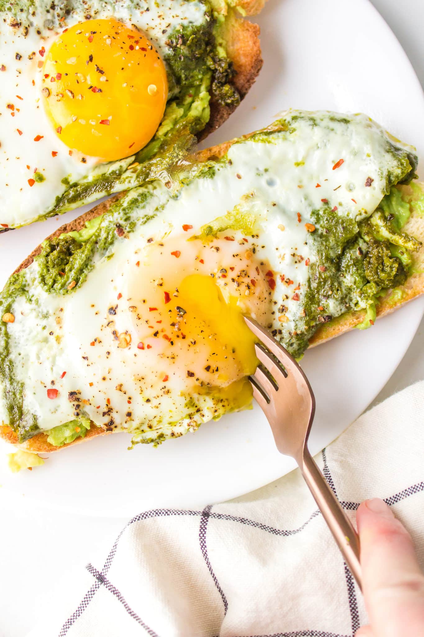 fork breaking into a cooked egg yolk on toast.