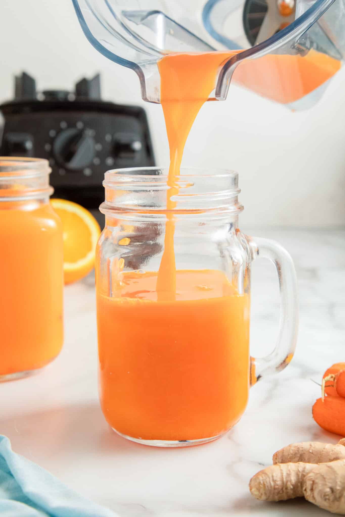 pouring carrot juice into a glass.