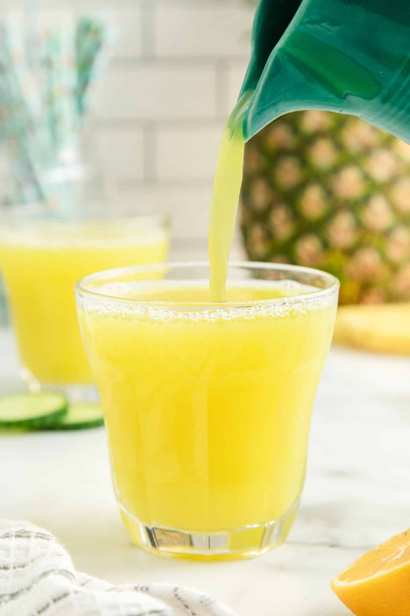pouring pineapple cucumber juice into a glass.