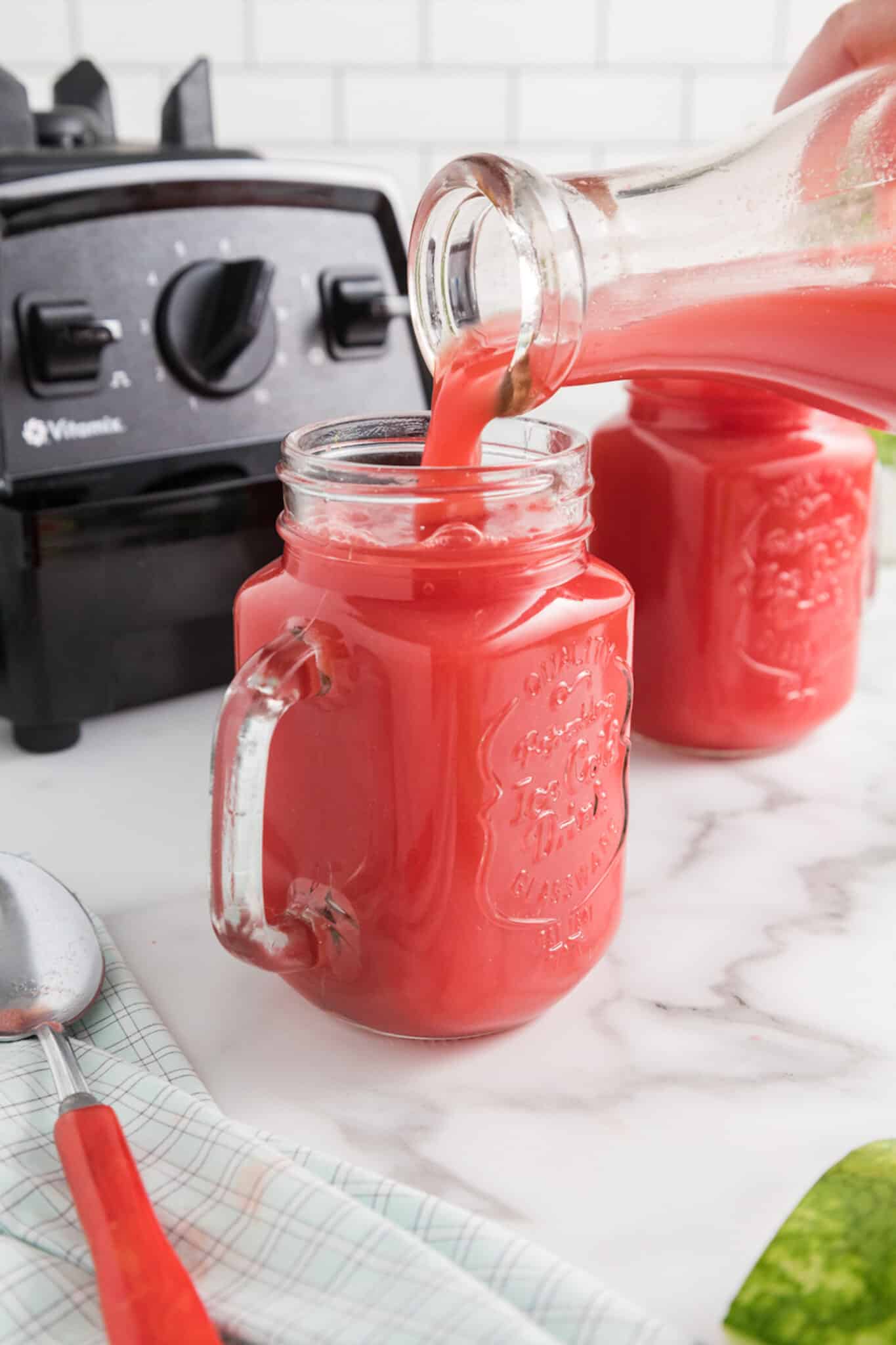 pouring fresh watermelon mint juice into a serving glass.