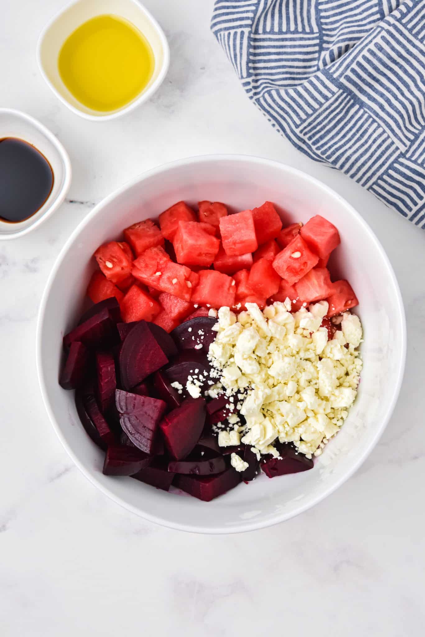 Beets, watermelon cubes, and crumbled feta in a white serving bowl.