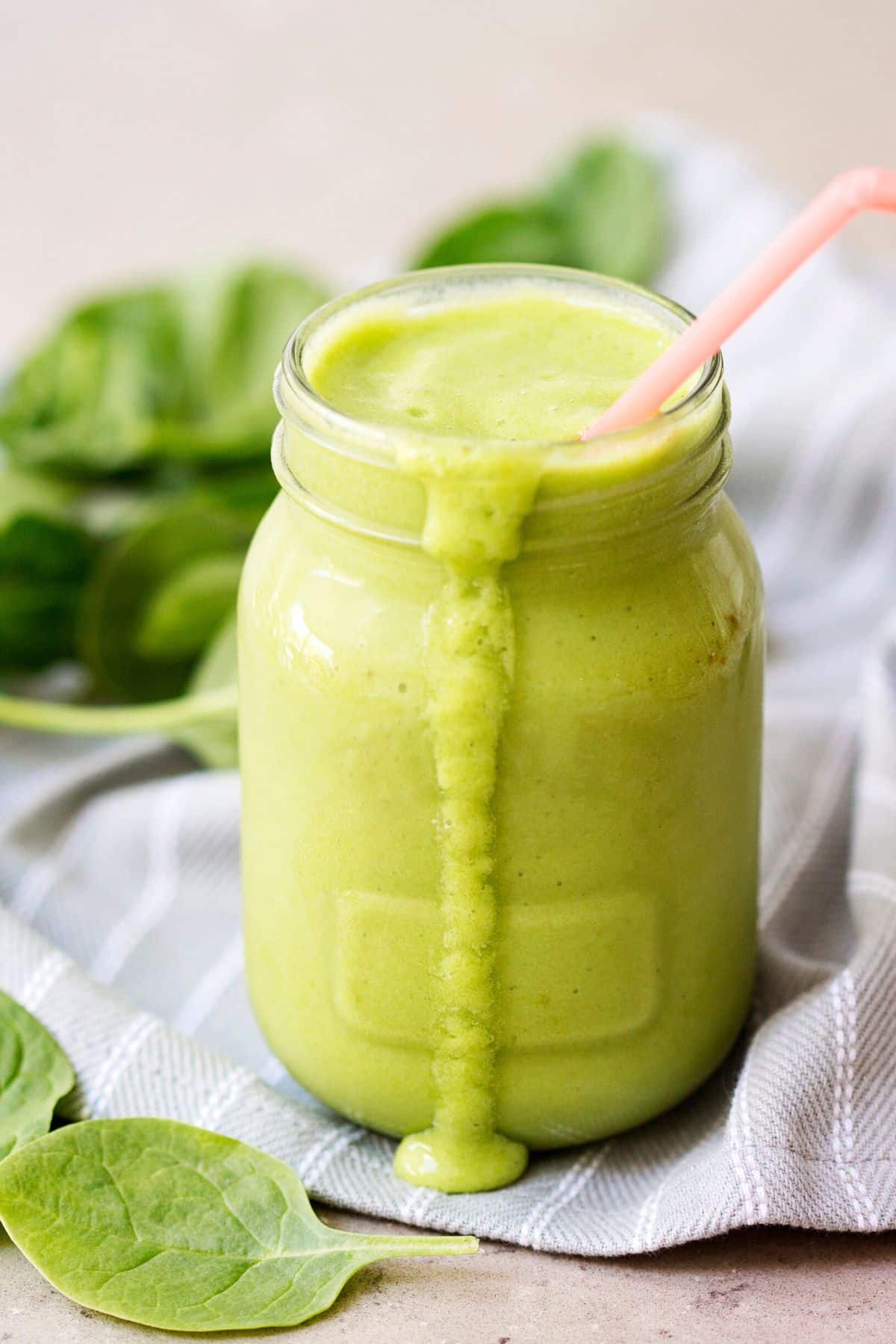 spinach and fruit smoothie in glass with straw.