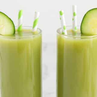 Two glasses of cucumber celery juice with cucumber wheels and straws.