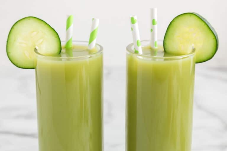 Two glasses of cucumber celery juice with cucumber wheels and straws.