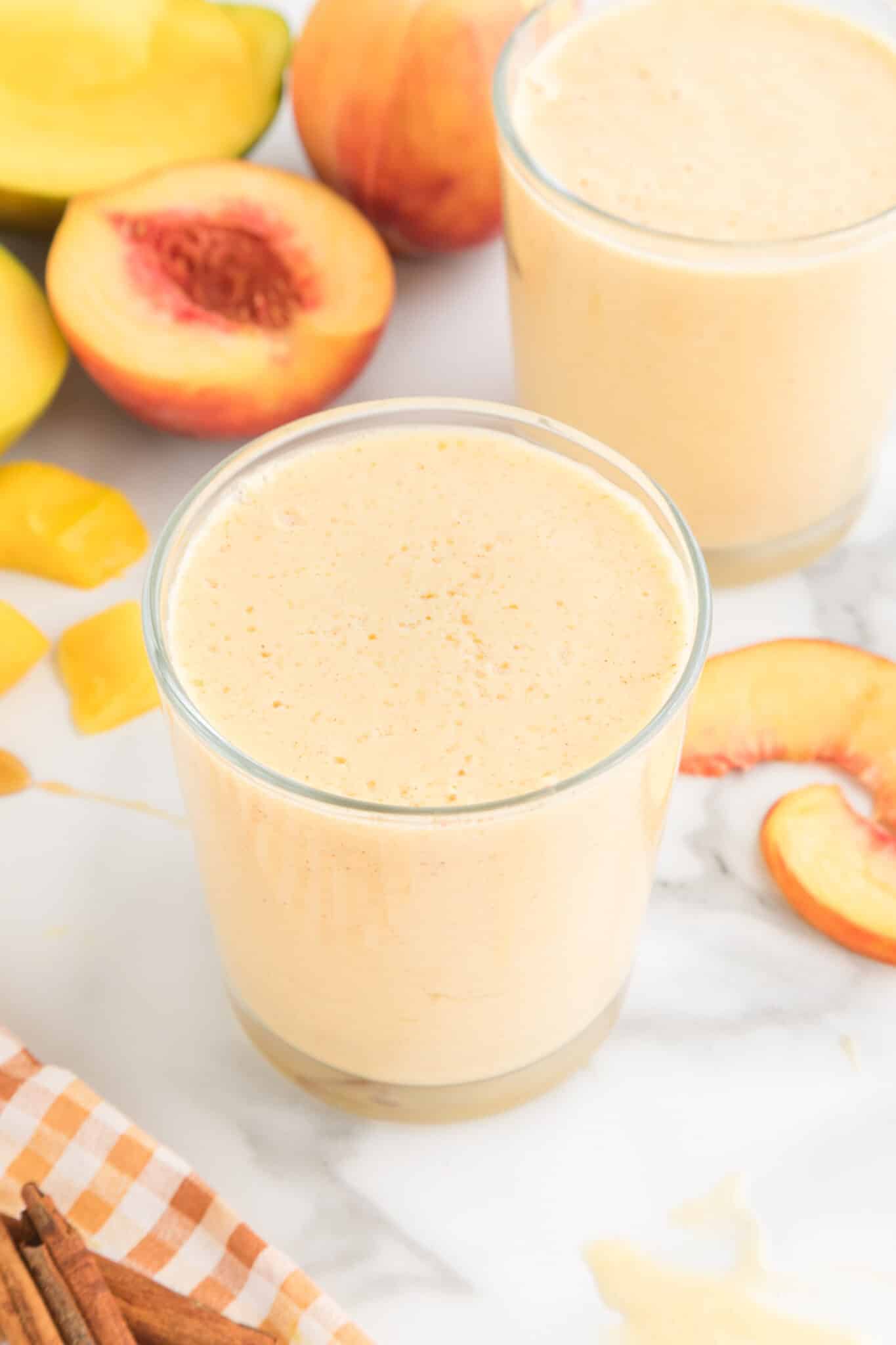 glass of mango peach smoothie on table.