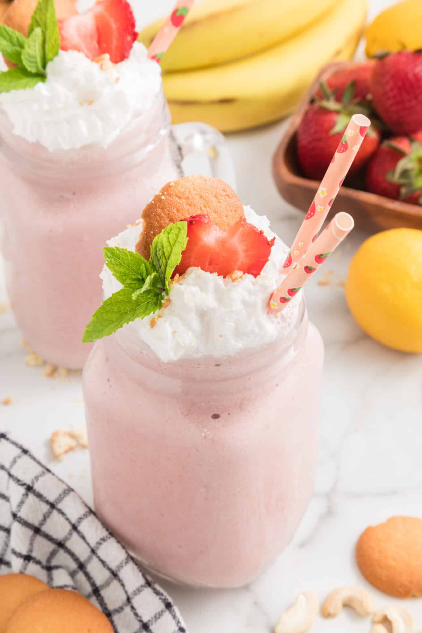 Vegan Strawberry Cheesecake Smoothie in a handled mason jar with two straws.