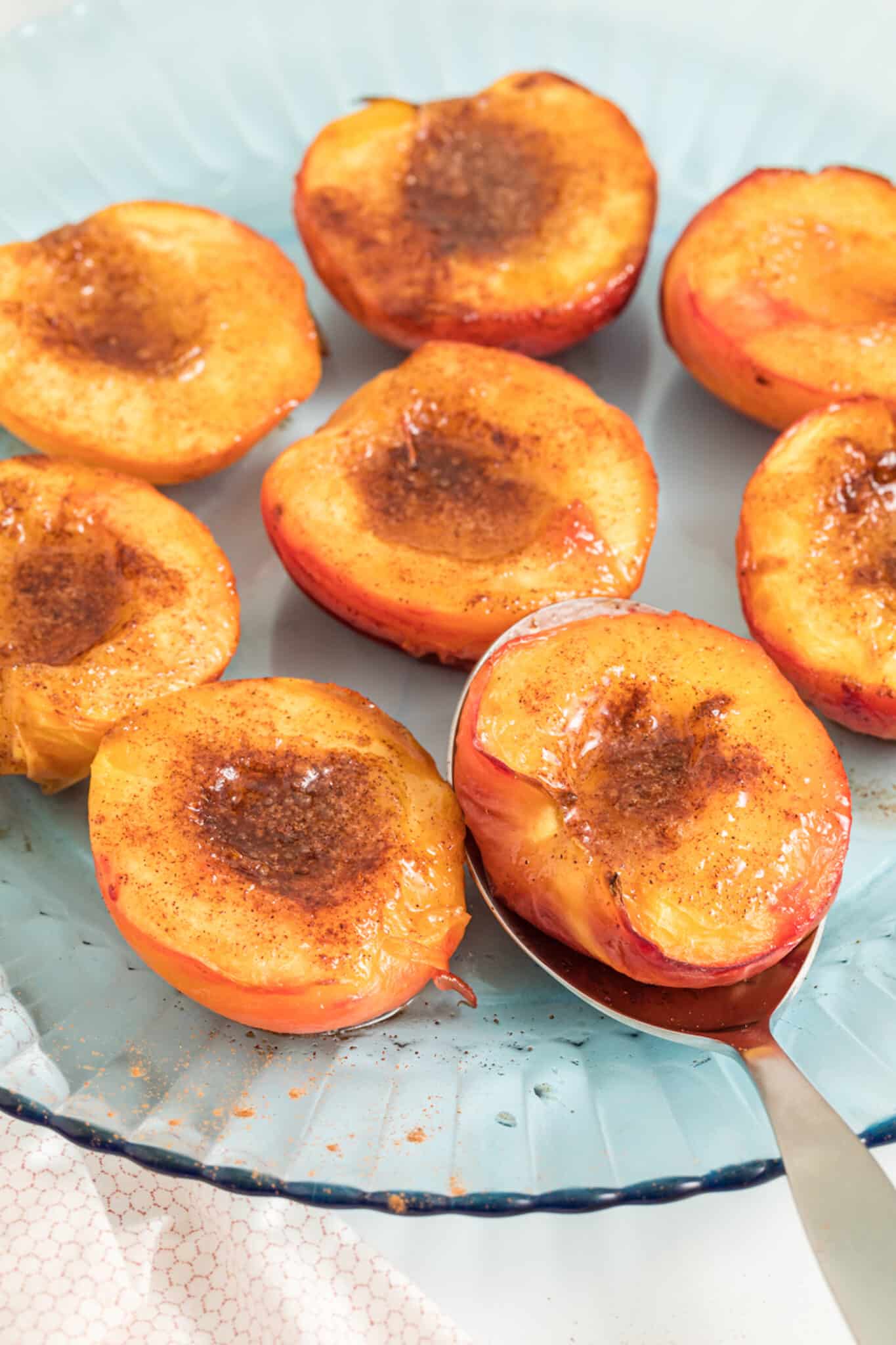 Caramelized air fryer peach halves on a serving platter.